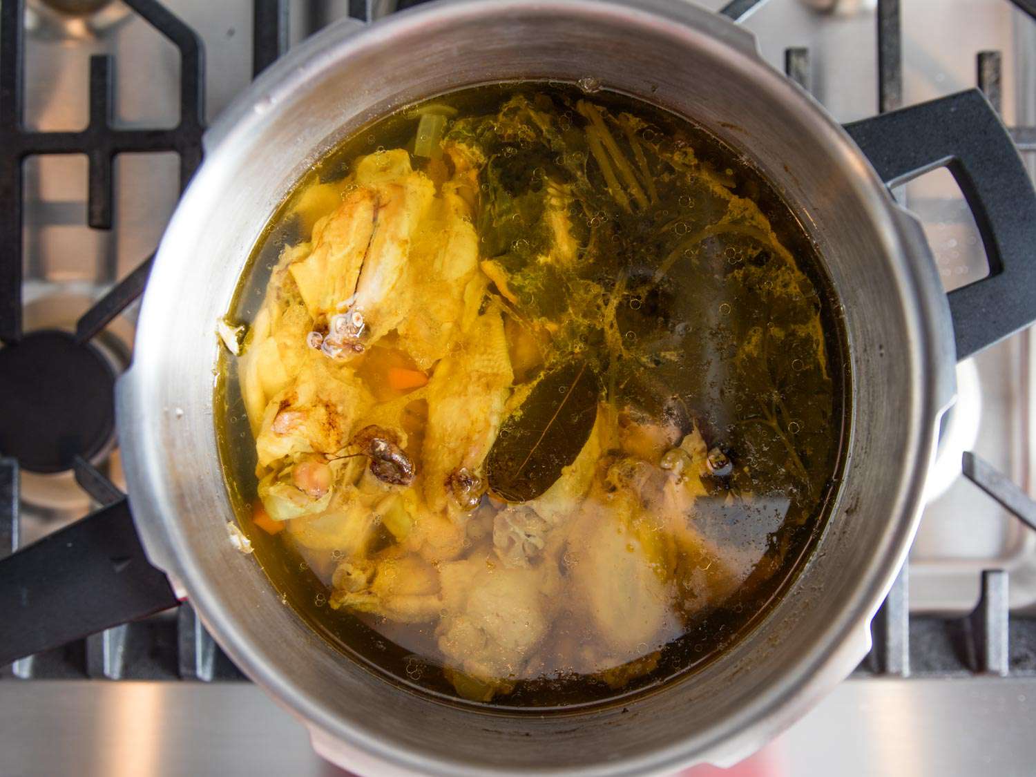 在炉顶高压锅中加压煮熟的鸡汤，准备好撇油和过滤。