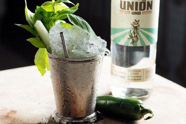 A mint julep made with basil and mezcal and garnished with basil, cucumber, and jalapeno.
