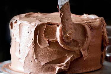 Frosting a cake with chocolate Swiss buttercream.