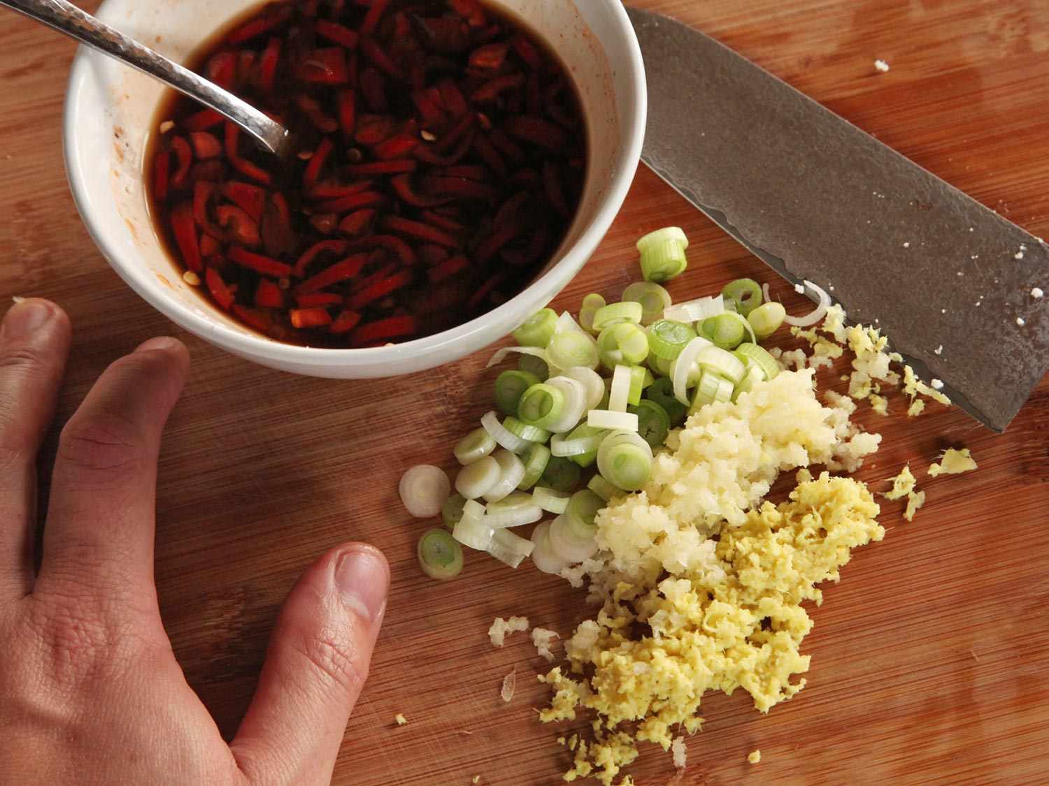 把泡椒和豆瓣酱放在一个准备碗里，旁边放上葱花、蒜末和姜末。
