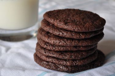 一叠薄薄的巧克力饼干，旁边放一杯牛奶