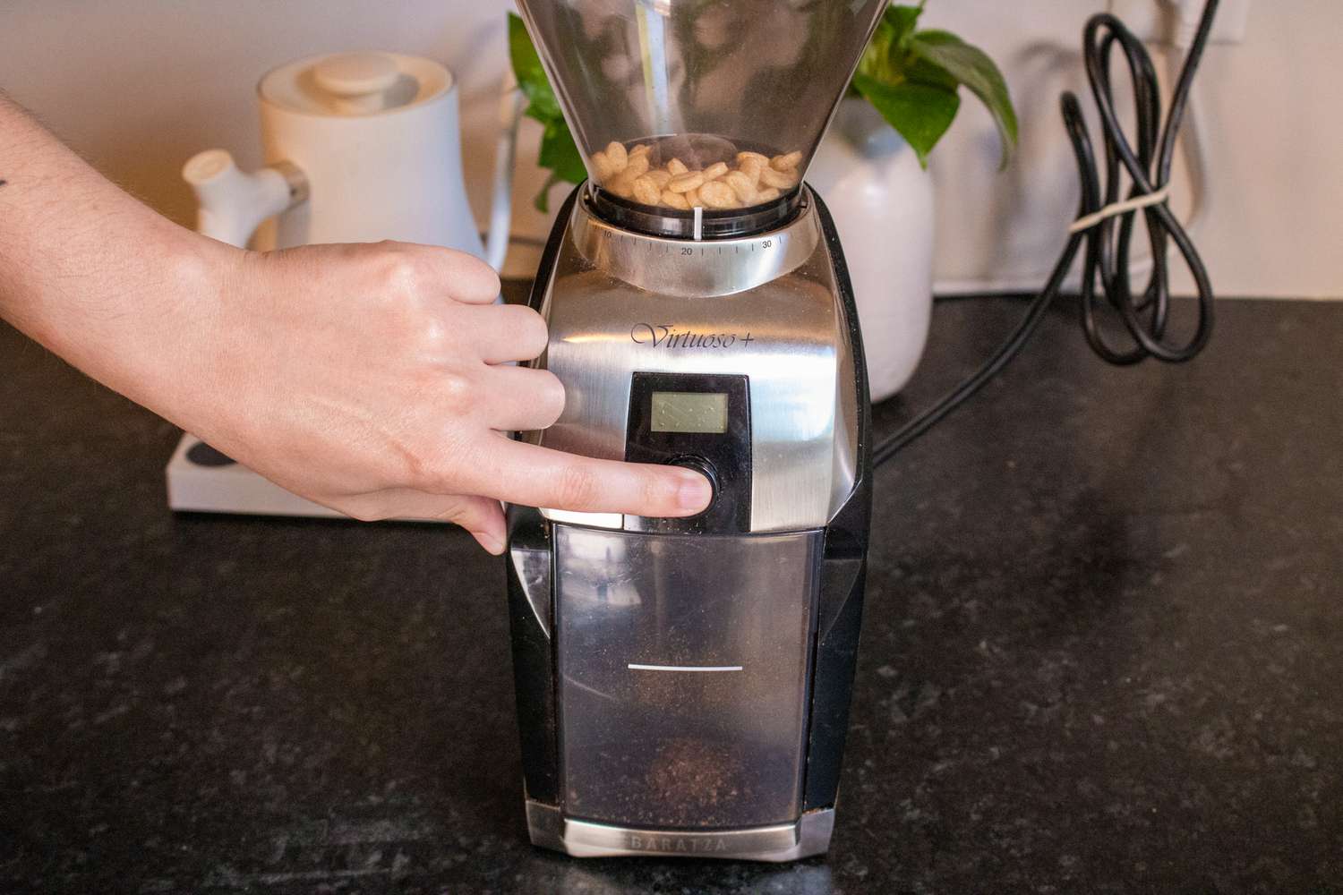 一只手按下咖啡研磨机的开始按钮