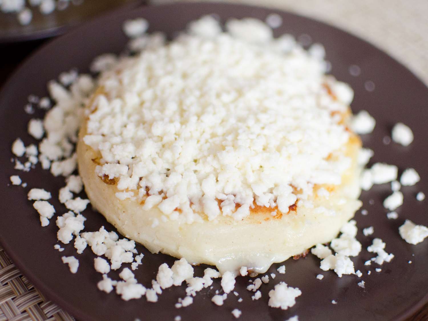 一份玉米饼放在小盘上，撒上大量的新鲜碎奶酪。