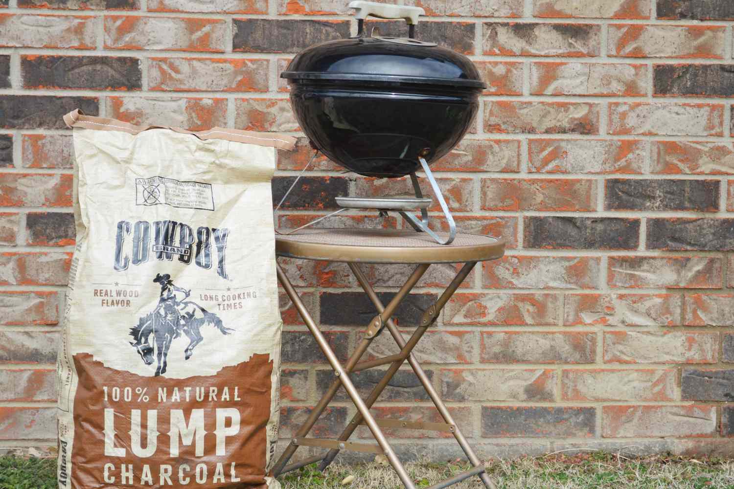 a bag of lump charcoal beside a portable charcoal grill