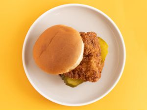 炸鸡三明治放在黄色背景的白色盘子里。