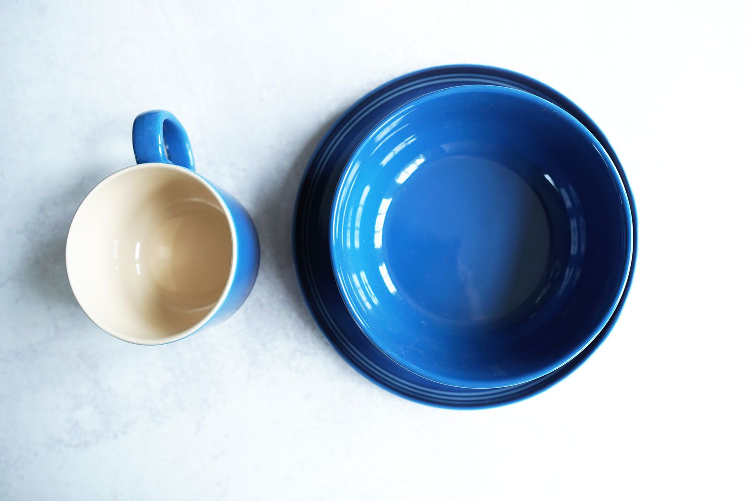 a blue bowl, plate, and mug on a grey background