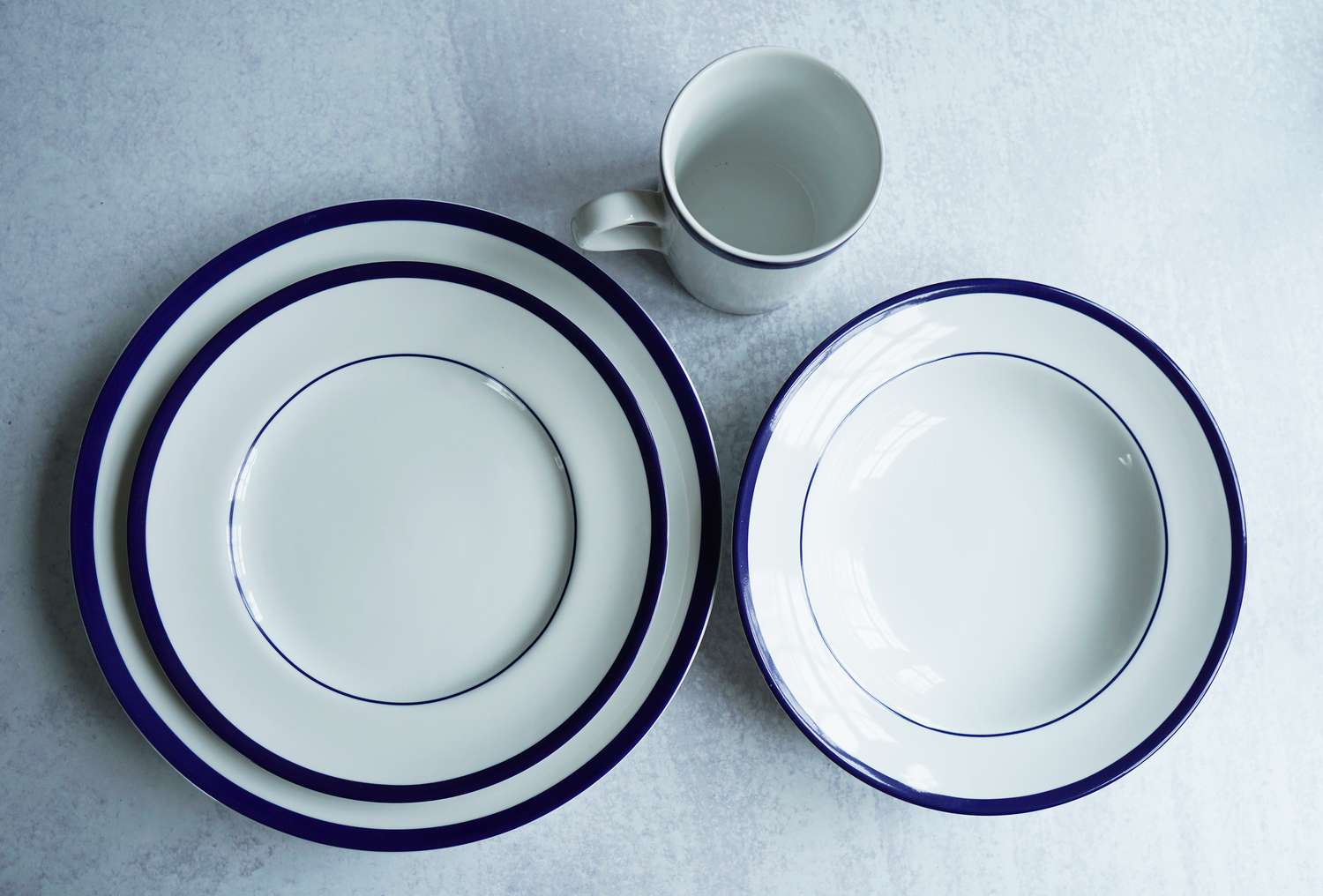 A white and blue dinnerware set on a grey surface