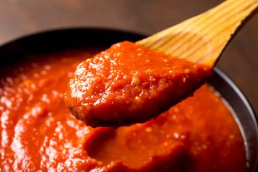 A wooden spoon scooping out a portion of quick and easy Italian-American red sauce that tastes like you spent all day making tomato sauce.