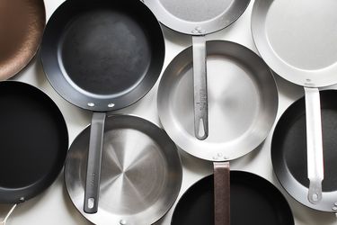 lineup of carbon steel skillets on a white surface