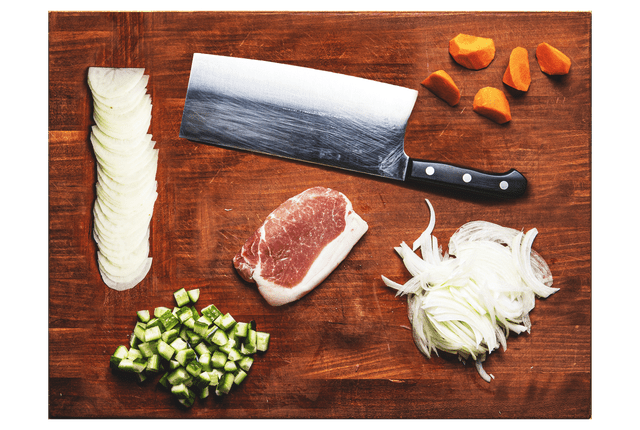 从俯视图看，切菜板上有一把刀和切碎的蔬菜和肉