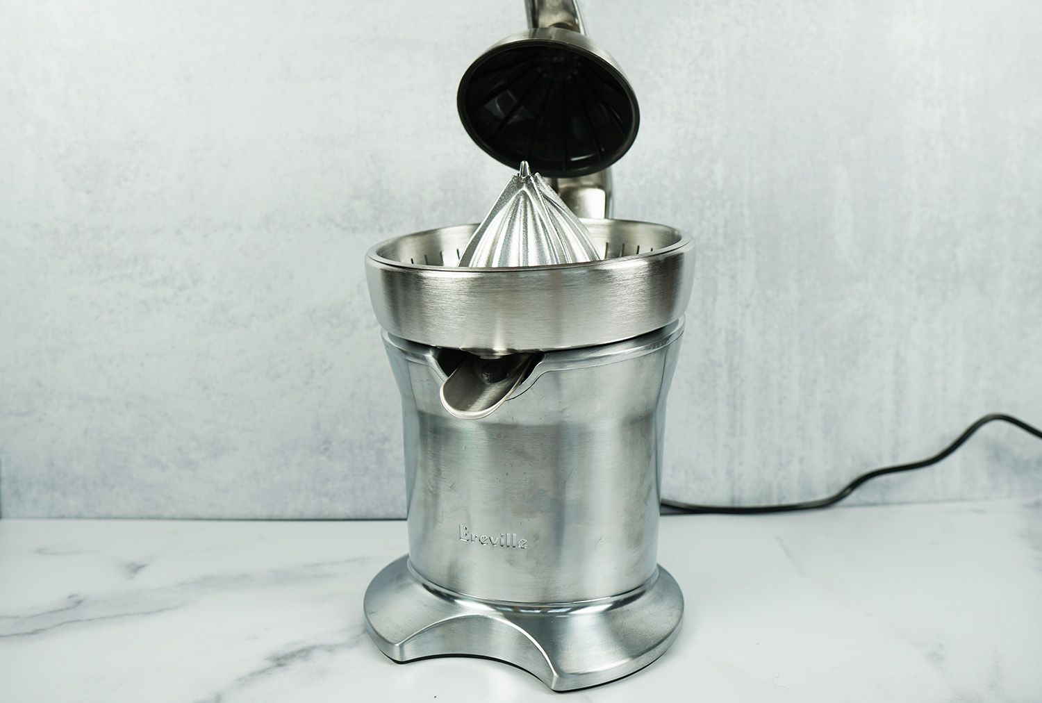 a stainless steel Breville electric citrus juicer on a marble surface