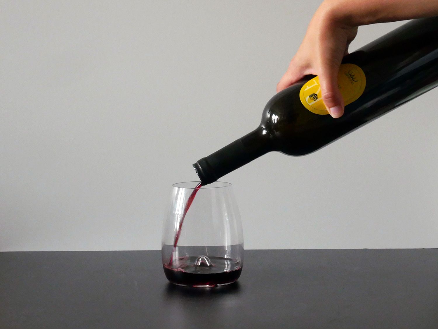 pouring red wine into waterford stemless wine glass