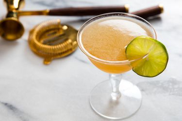 A daiquiri With Scotch and maple served in a cocktail glass with a lime wheel.