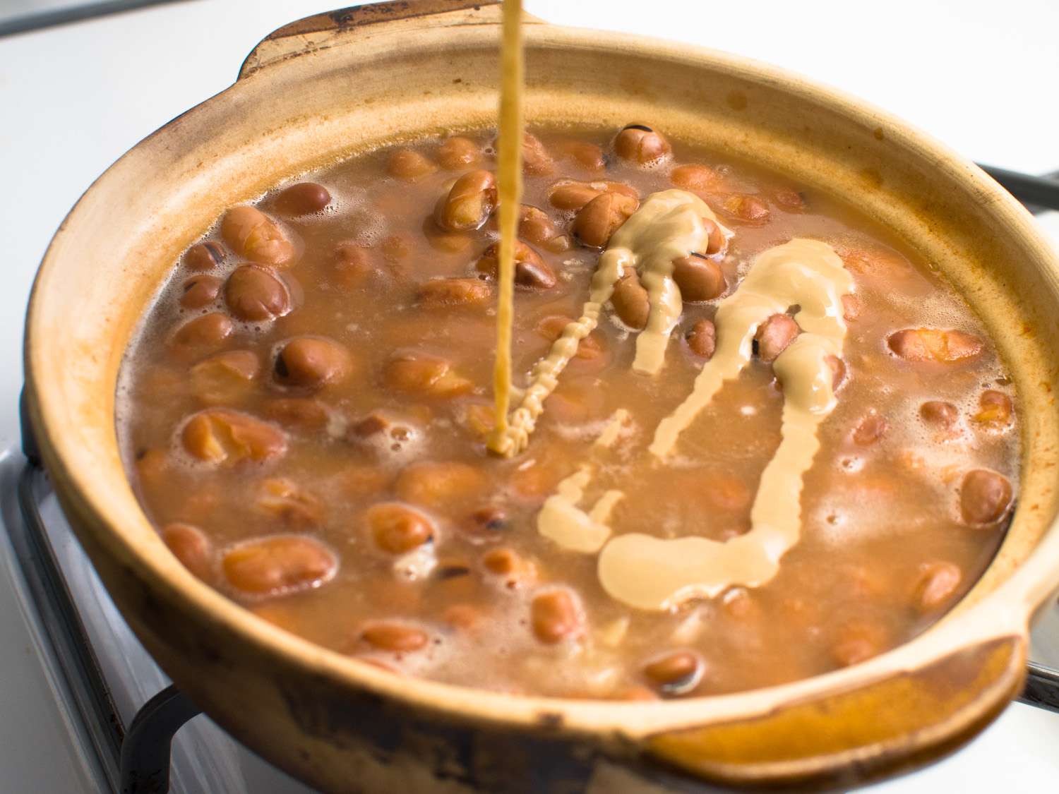 芝麻酱添加到一锅炖蚕豆。
