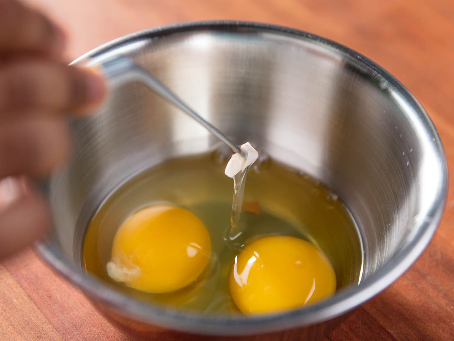 镊子从盛有鸡蛋的碗中取出一块蛋壳