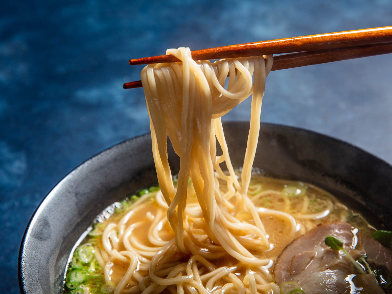 用筷子从一碗拉面中夹出自制的碱性面条
