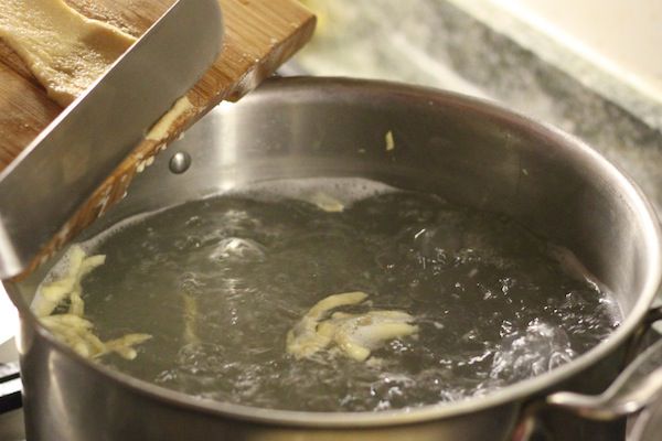 将spätzle面糊切成细条，放入水中煮沸。