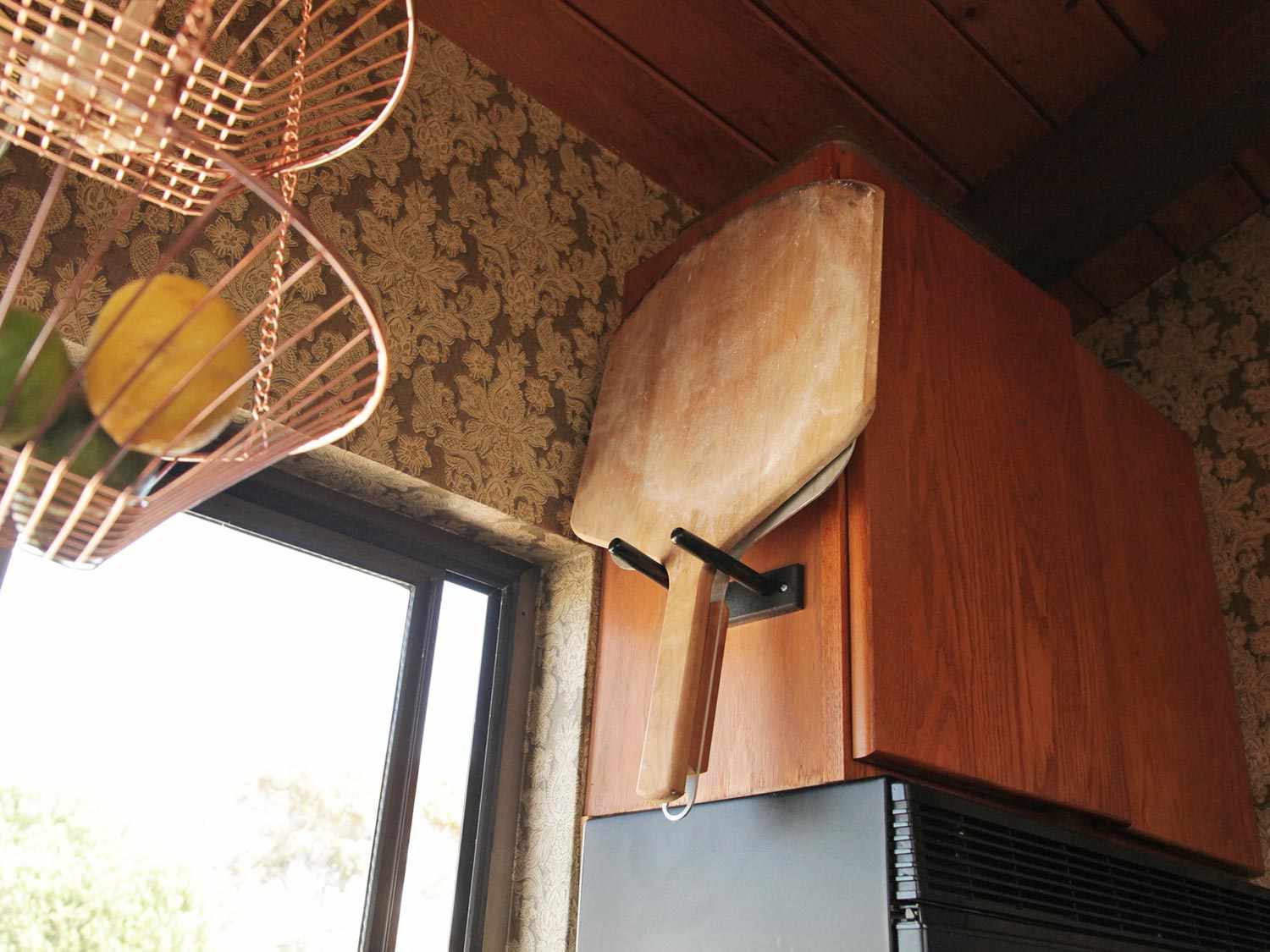木制和金属披萨皮挂在厨房橱柜旁