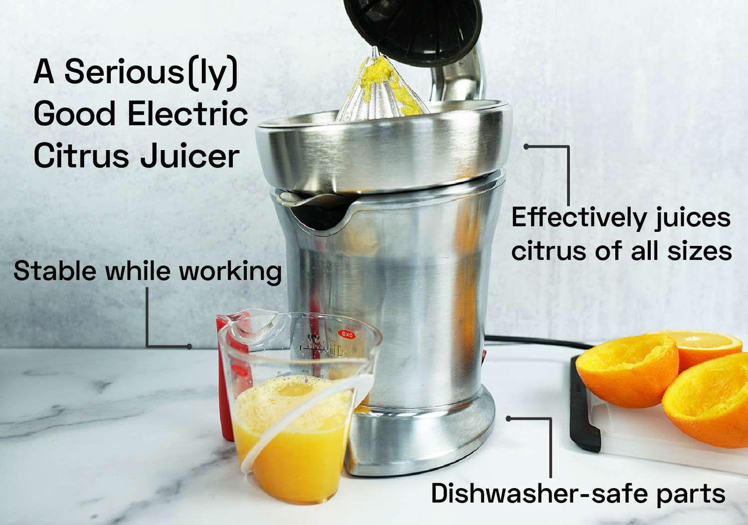 an electric citrus juicer with citrus pulp on its reamer and a cup of orange juice below it