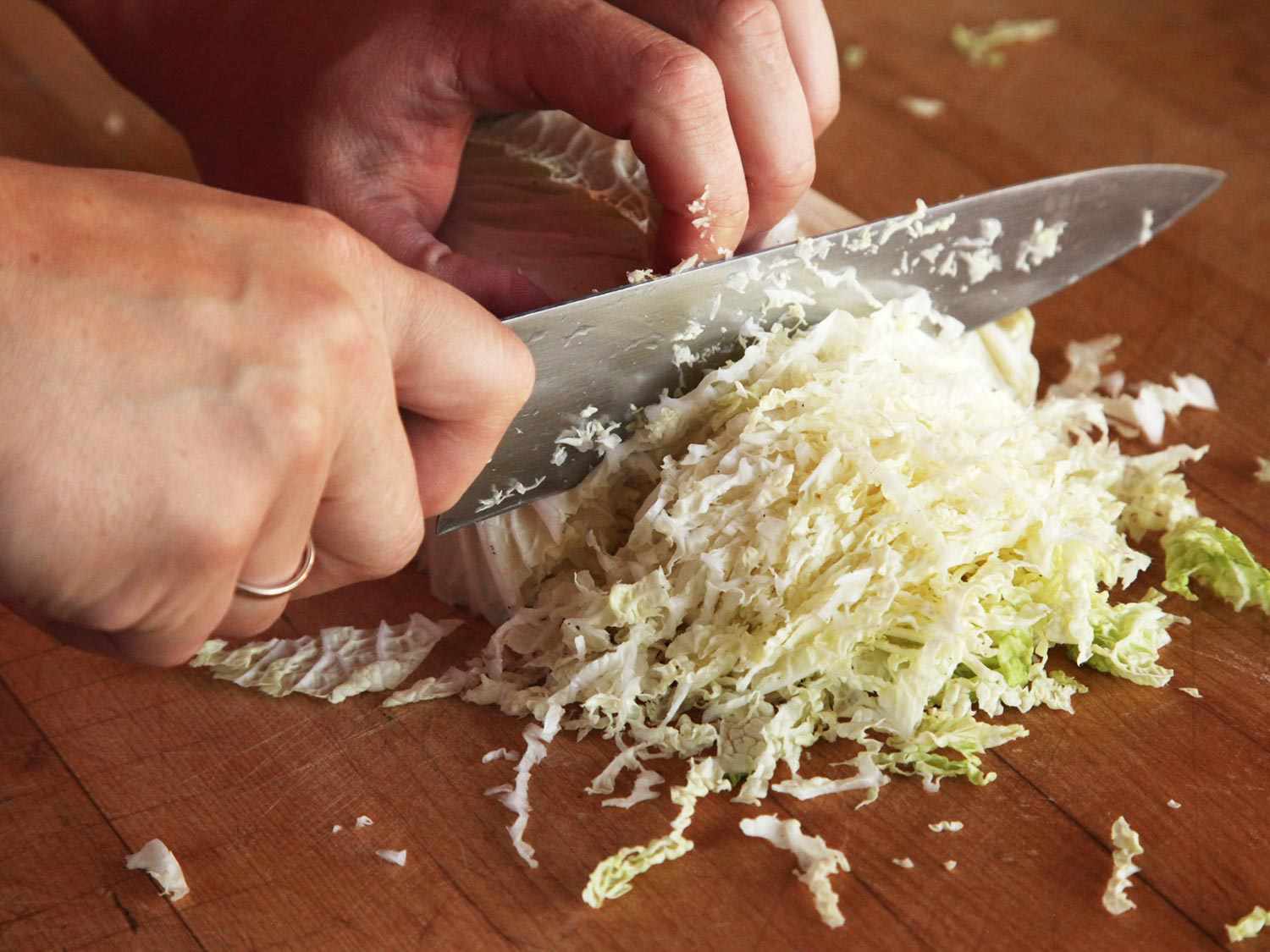 在切菜板上用刀将大白菜切碎。