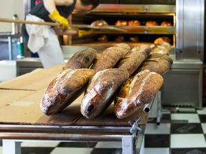 面包在贝克的桌子在厨房Tartine面包店。在后台,有人使用长柄皮饼在商业烤箱。