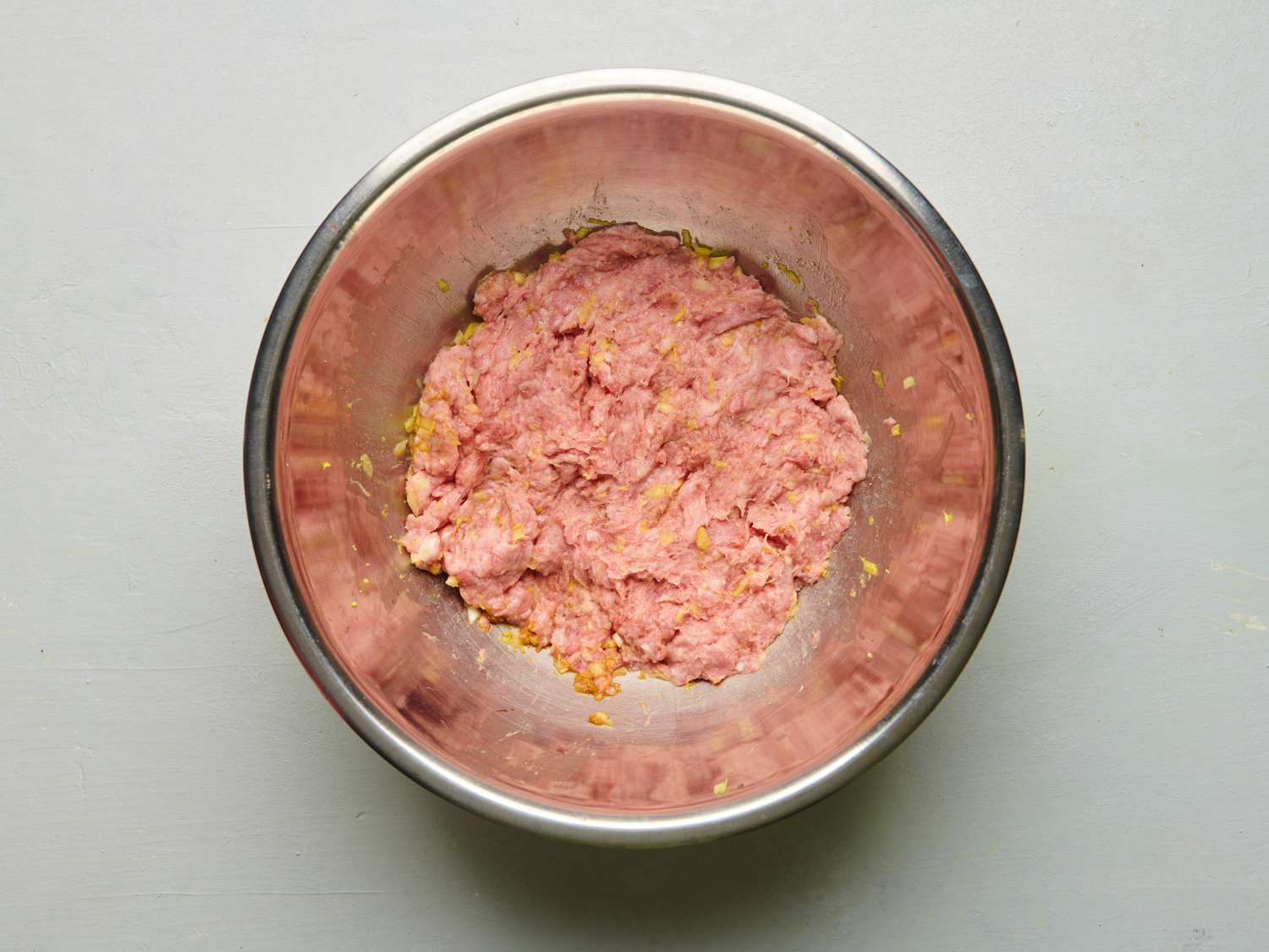 猪肉、磨碎的鲜姜、糖、酱油、香油、一半香葱和剩下的1茶匙盐混合在一个中等大小的金属碗里。