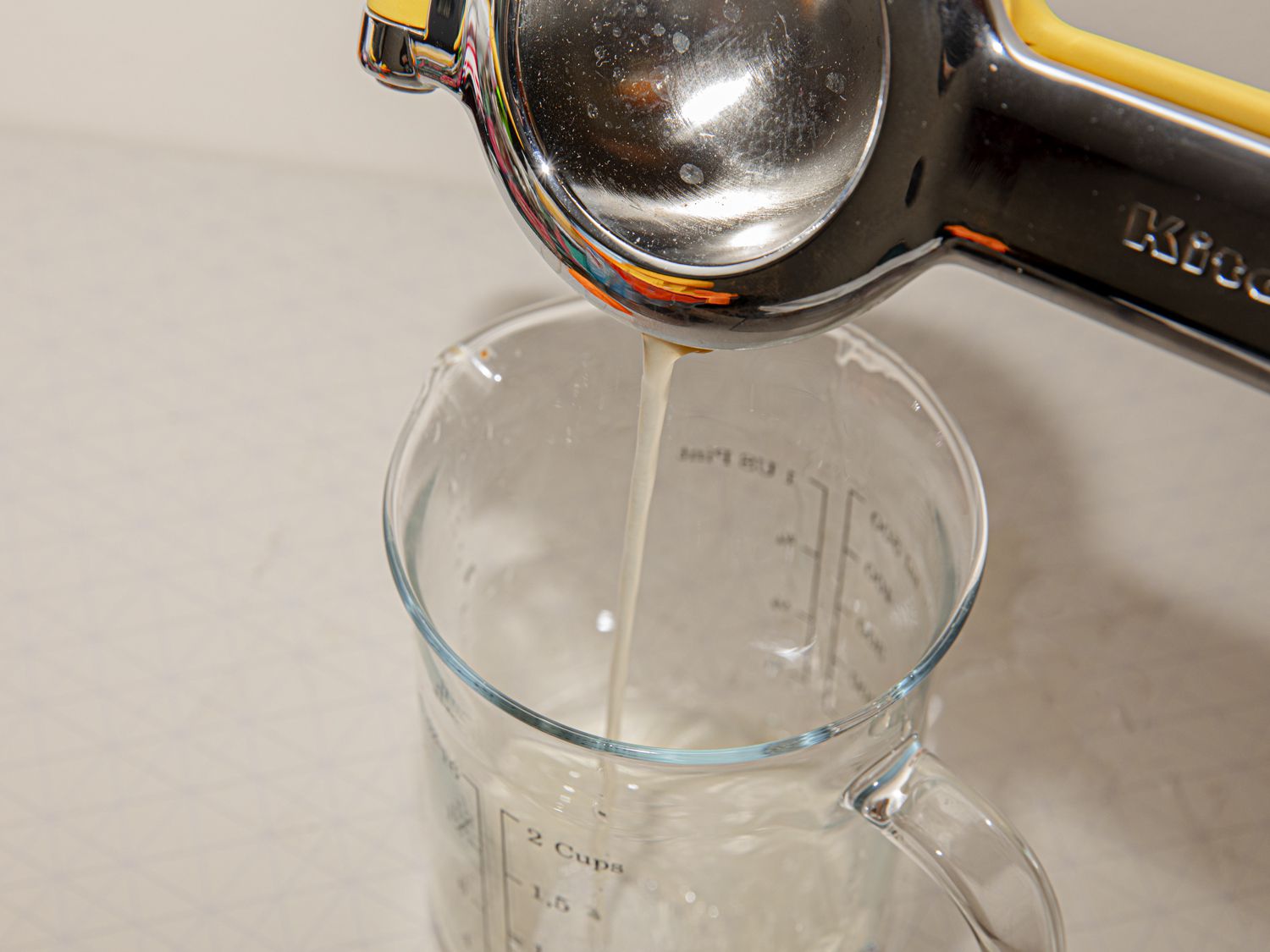 手持柑橘榨汁机将果汁倒入玻璃量杯中
