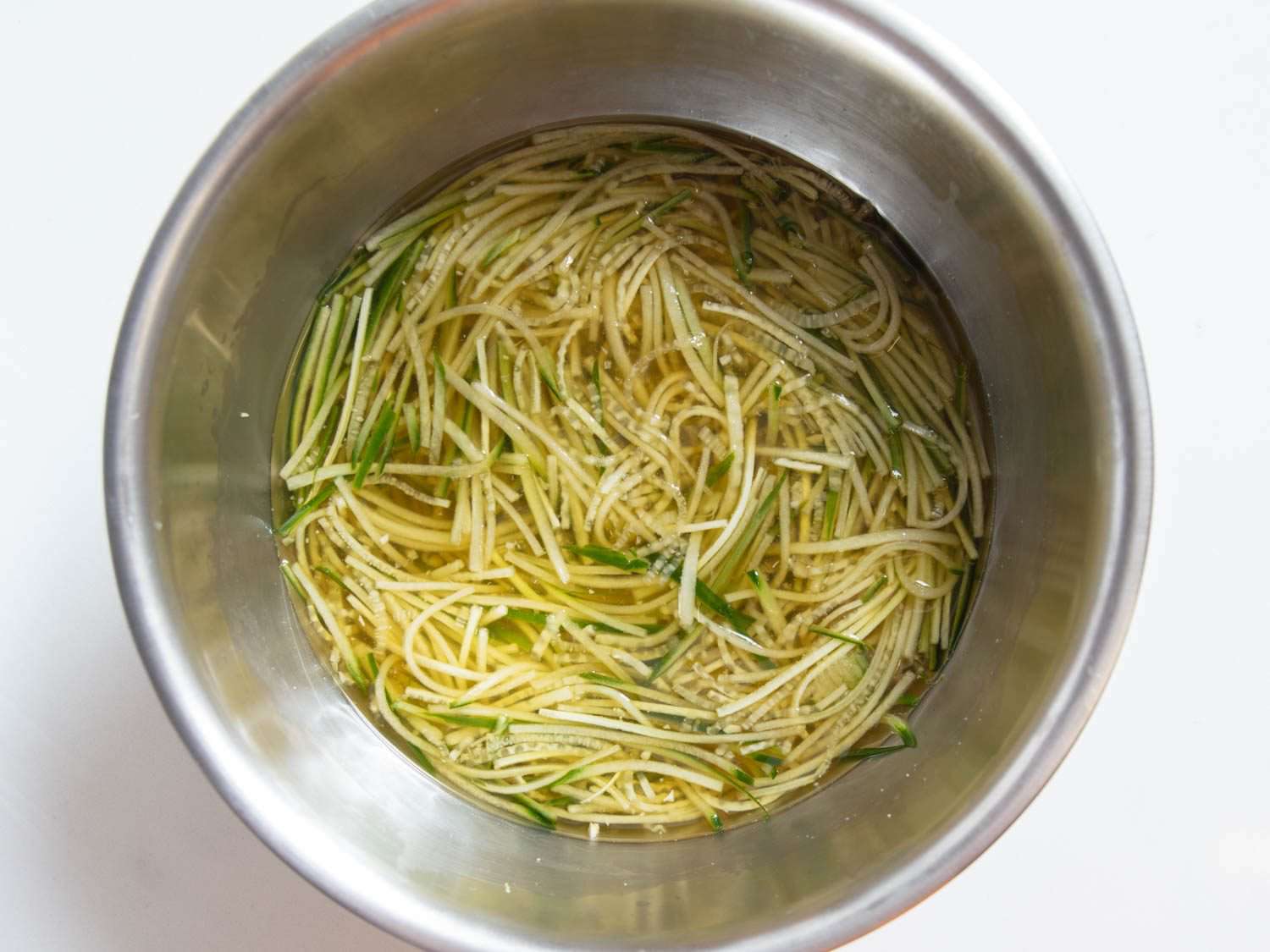 Oi naengguk,冷冻韩黄瓜汤,还在冰前的碗里已经添加到薄的黄瓜和轻经验丰富的汤。