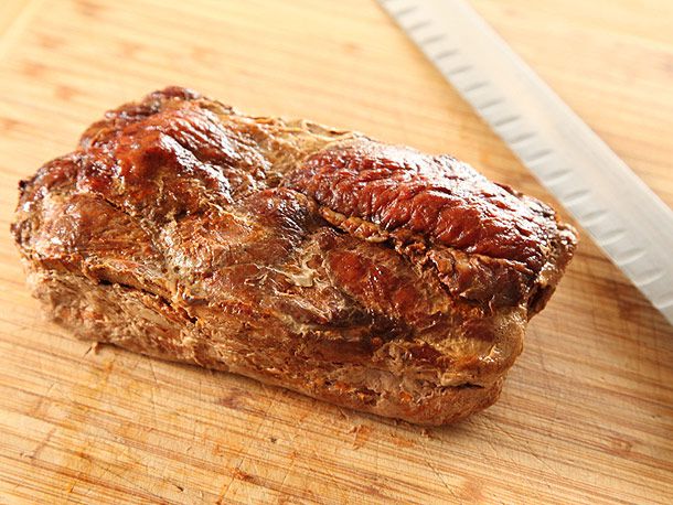 烤好的牧师肉放在木砧板上，旁边放着一把刀。
