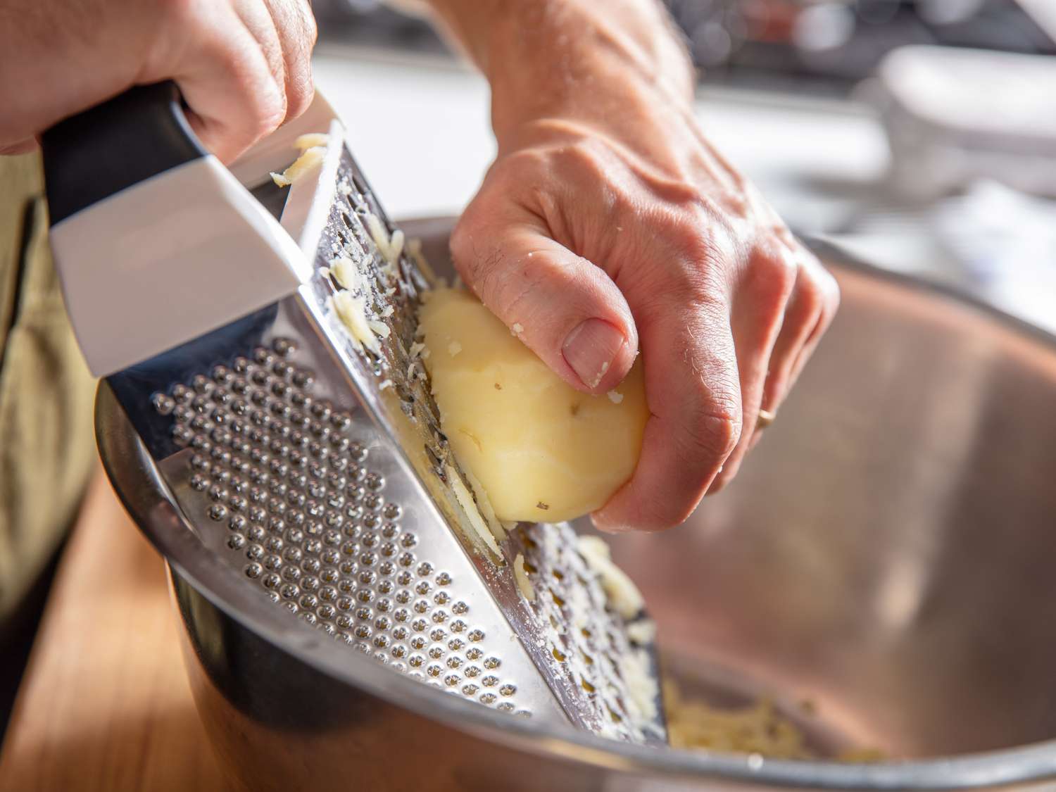 Grating cooked and peeled Yukon Gold potatoes for rÃ¶sti.