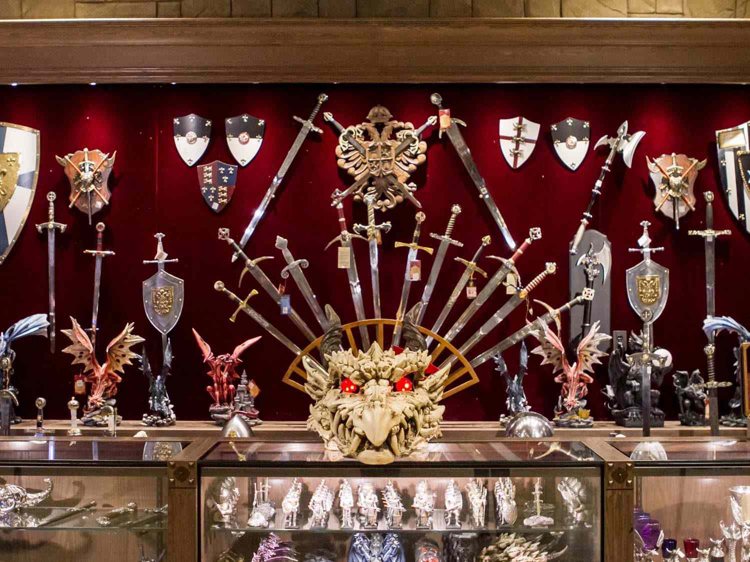 中世纪礼品店里的物品:墙上陈列着一排剑、盾牌和斧头，还有龙雕像和一个大的