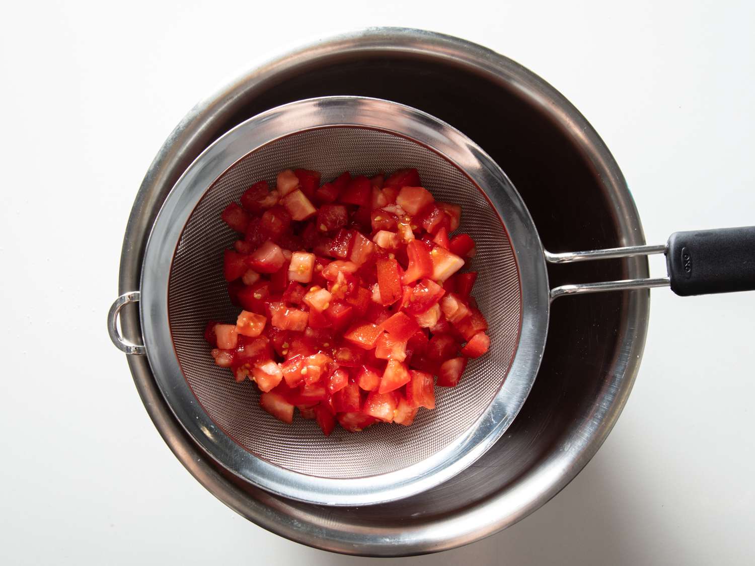 将切碎的西红柿用盐调味，放在碗上的细网过滤器中，以释放多余的液体gydF4y2Ba