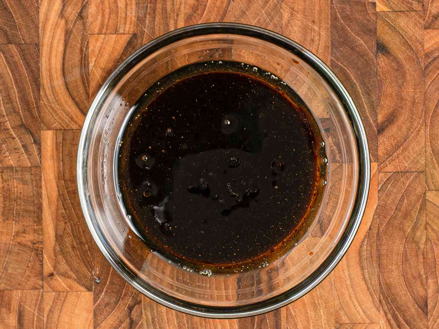 香油、生抽和老抽、蚝油、盐、糖、酒和水混合在一个小玻璃碗里，放在木砧板上。