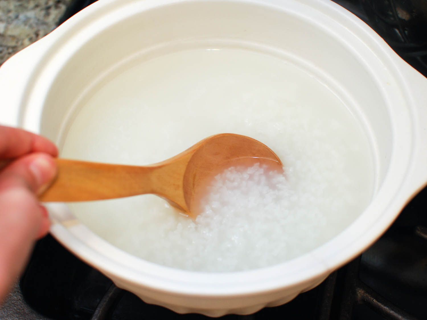 Stirring short grain rice in water for congee.