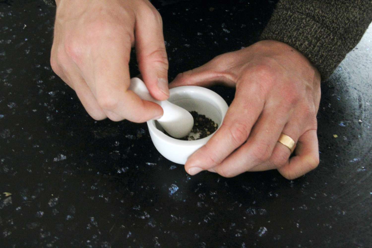 手用很小的杵粉碎黑胡椒在一个很小的砂浆。
