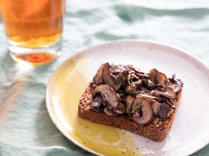 一片丹麦黑麦面包的面包加上炒蘑菇,旁边一杯啤酒
