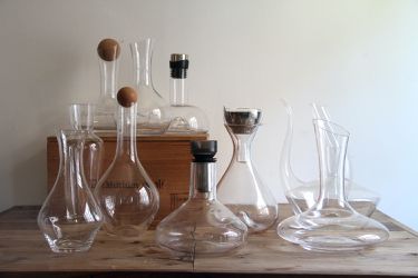 a group of glass wine decanters on a wooden surface