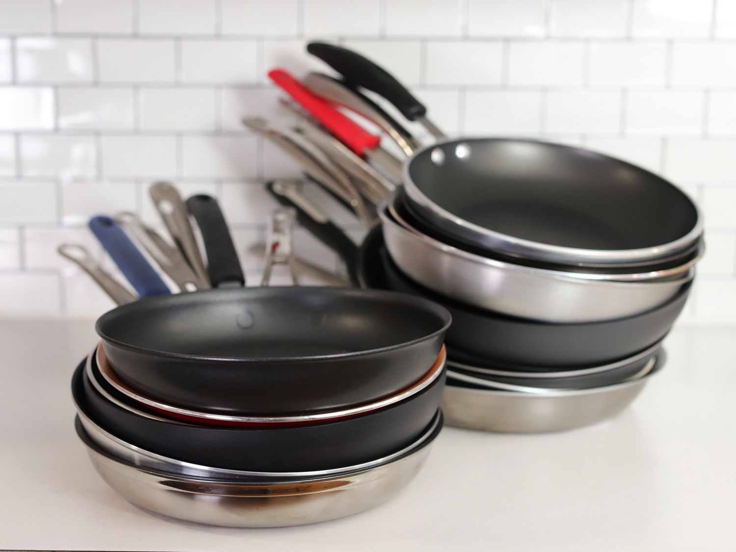 two stacks of various nonstick skillets against a white background