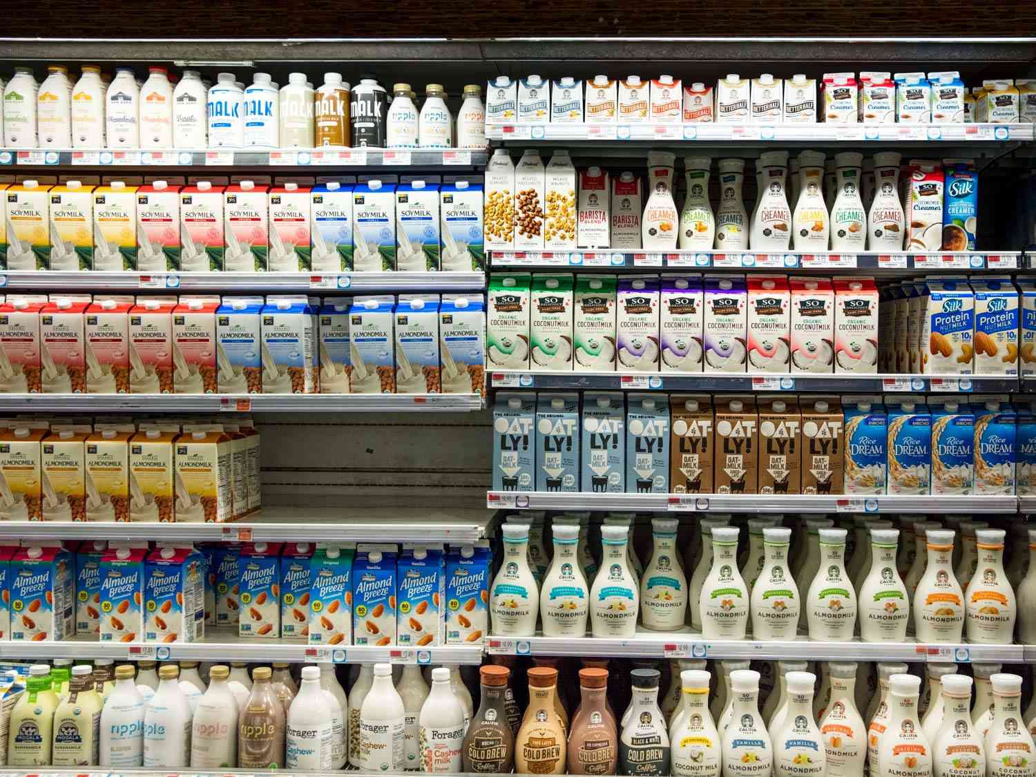 超市货架上摆满了各种各样的非乳制品牛奶，包括杏仁奶、燕麦奶、椰奶、豆奶和米奶