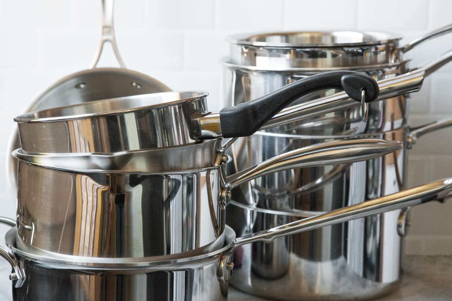 two stacks of stainless steel saucepans on a kitchen countertop