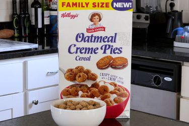 Box of Kellogg's Little Debbie Oatmeal Creme Pies cereal on a counter with a bowl of cereal in front of box