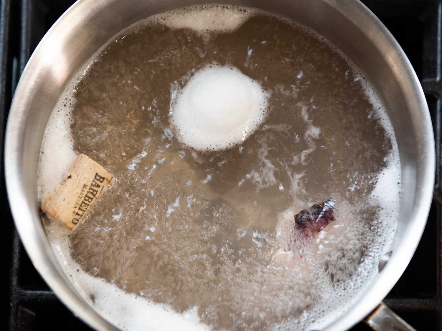 看着炉子上一个沸腾的锅，水里有一块章鱼和一个软木塞。