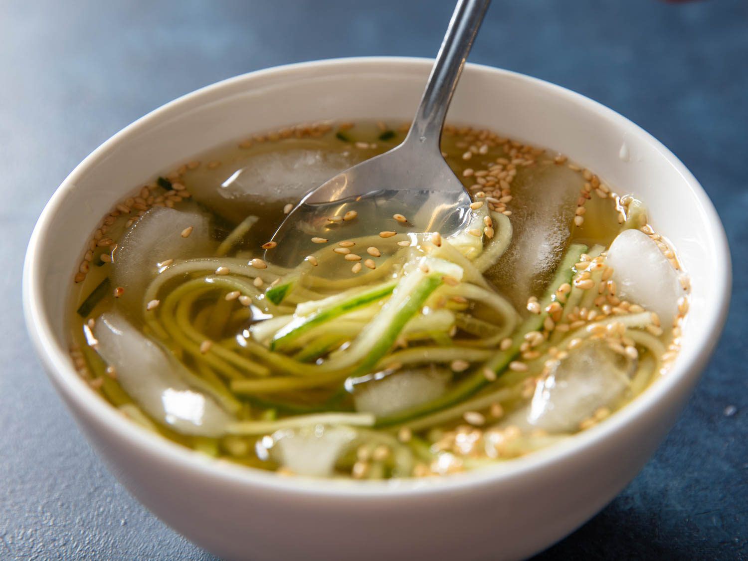 勺子喝到一碗oi naengguk,冰冷的冷韩国汤,将冰块漂浮在黄瓜和汤的碗