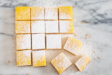 开销图像显示切片柠檬酒吧方格加上糖粉在大理石工作台面。