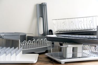 a bunch of dish racks against a white background and on a wooden countertop