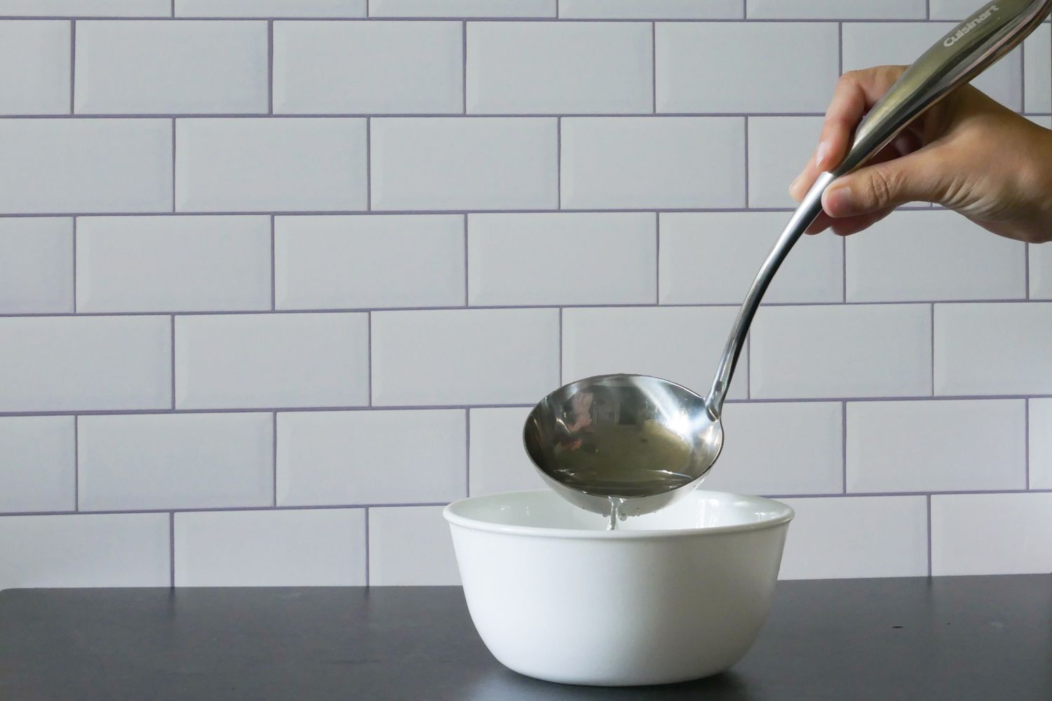 用长柄勺把水倒进碗里，演示碗的形状。