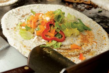 A homemade dosa topped with fresh vegetables