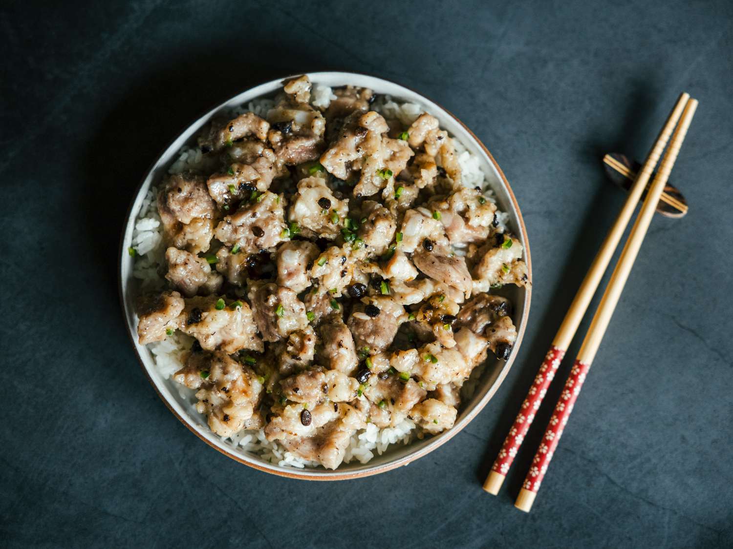 俯视图蒸排骨在一盘米饭旁边放置一双筷子。＂class=