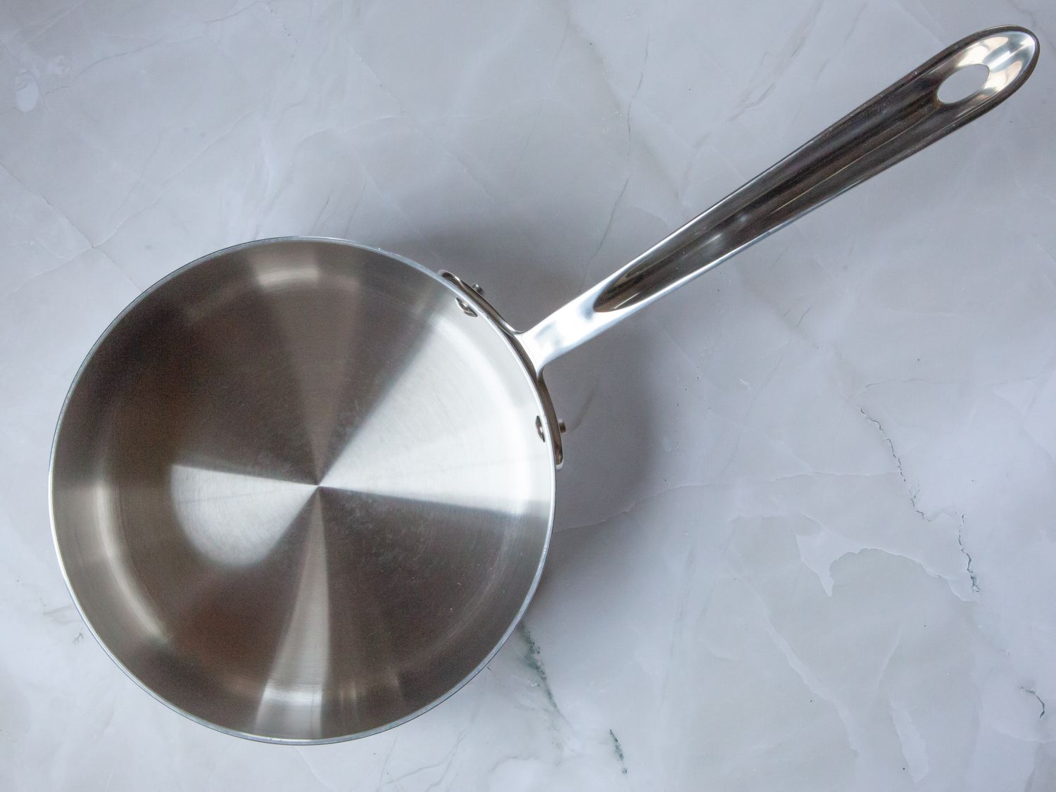 a stainless steel saucepan on a marble surface
