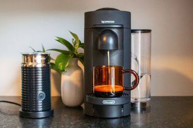 A wide-angle shot of a Nespresso machine brewing into a mug with a milk frother beside it